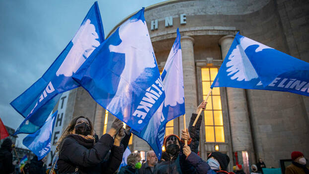 Hellblaue Fahnen mit einer weißen Friedenstaube werden geschwenkt.